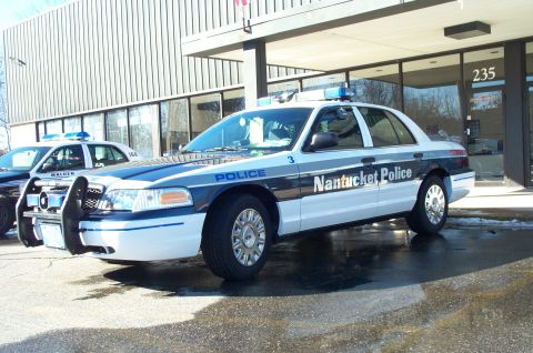 2001 Ford Crown Victoria - A Nantucket Police 2001 Ford Crown Victoria is parked outside a building, with another police car visible to its left.