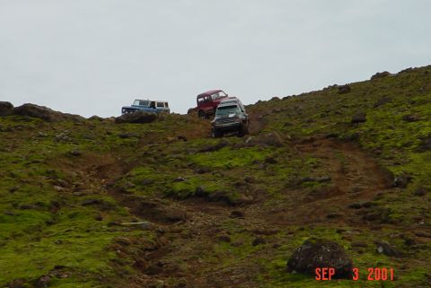 1993 Ford Bronco - Multiple off-road vehicles navigate a challenging, rocky terrain on a hillside.