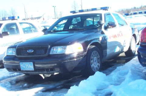 2001 Ford Crown Victoria - A police car with a light bar and 'POLICE' markings is parked in a snowy lot, with another police vehicle nearby.