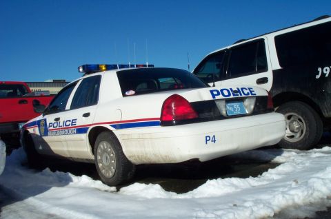 2001 Ford Crown Victoria - A 2001 Ford Crown Victoria police car is parked in the snow next to another vehicle.