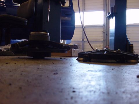 1998 Volkswagen Jetta - Two car parts are on the floor of a garage, near a vehicle and a lift.