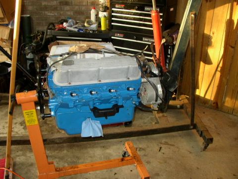 1995 Ford Bronco - Engine on a stand in a garage setting, with tools and cabinets in the background.