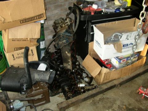 1995 Ford Bronco - Various engine parts and boxes are stored in a cluttered garage space.