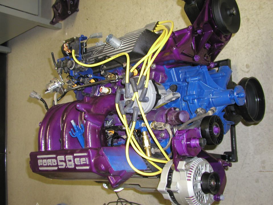 Purple-painted Ford 5.8 EFI V8 engine on a stand with yellow plug wires and chrome alternator