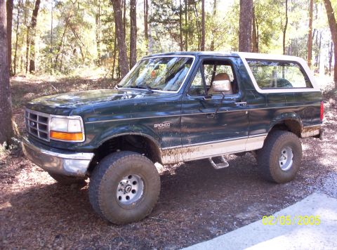 1993 Ford Bronco - This 1993 Ford Bronco is shown off-road in a wooded area with dirt and mud on its tires and lower body panels.
