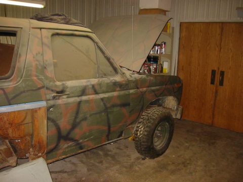 1984 Ford Bronco - This SUV is covered in a camouflage paint scheme and appears to be undergoing some work in a garage.