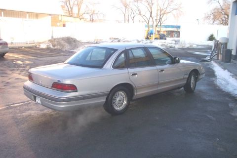 1992 Ford Crown Victoria - This sedan is seen from a three-quarter front angle, with steam or exhaust visible near the rear wheel.