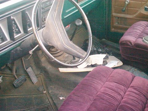 1991 Ford Bronco - The interior of an older vehicle shows its dashboard, steering wheel, and front seats. The floor mats are dirty.