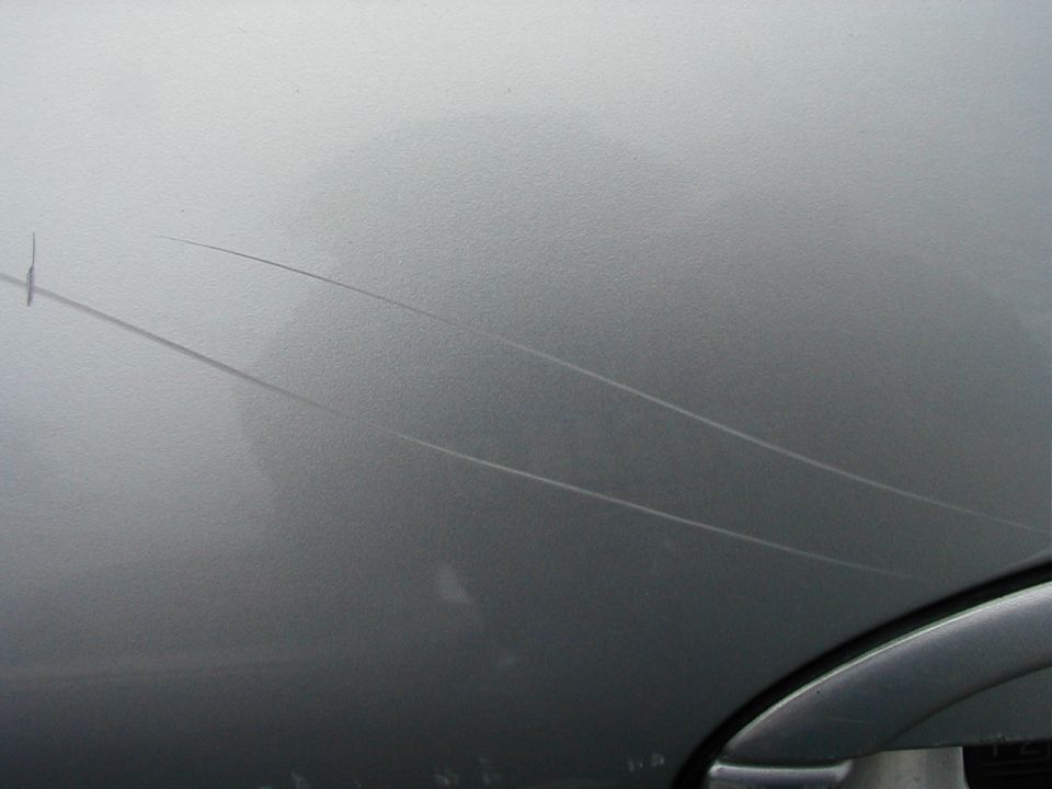 Close-up of scratches on a silver car's body panel
