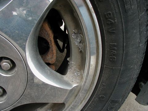 1997 Ford Taurus - A close-up view of a vehicle's wheel and tire, showing corrosion on the alloy rim and tire sidewall text.