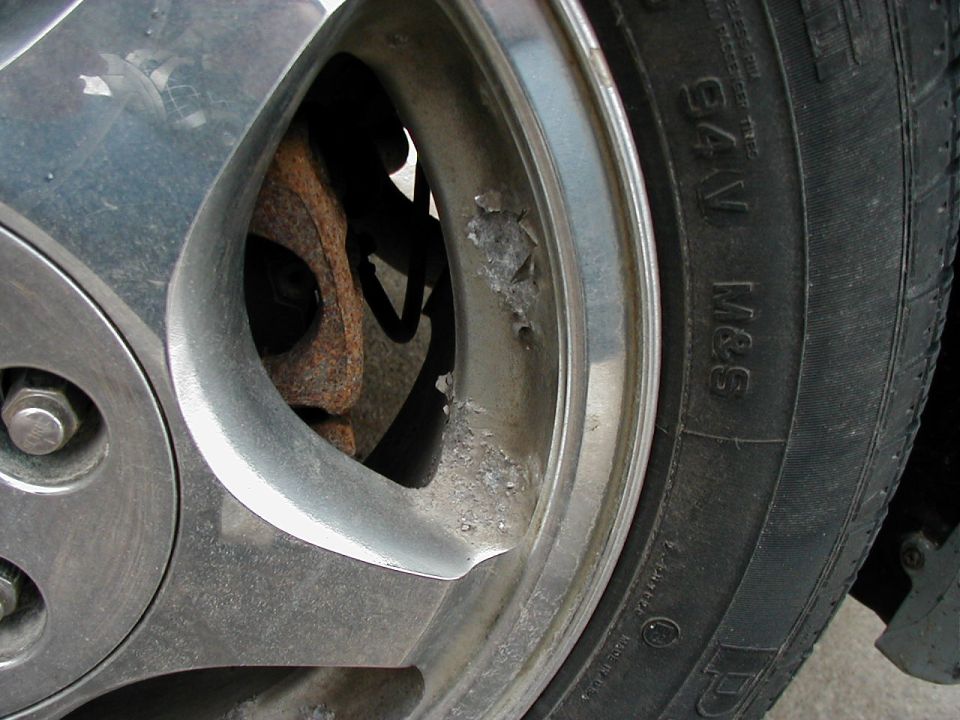 Close-up of a corroded alloy wheel and tire with sidewall markings