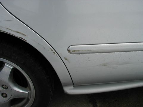 1997 Ford Taurus - Scuffs and dirt mar the side of a silver 1997 Ford Taurus.