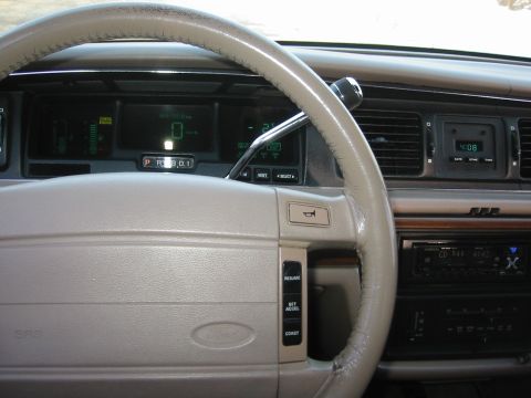 1992 Ford Crown Victoria - The interior of a 1992 Ford Crown Victoria shows a digital dashboard and a beige steering wheel.