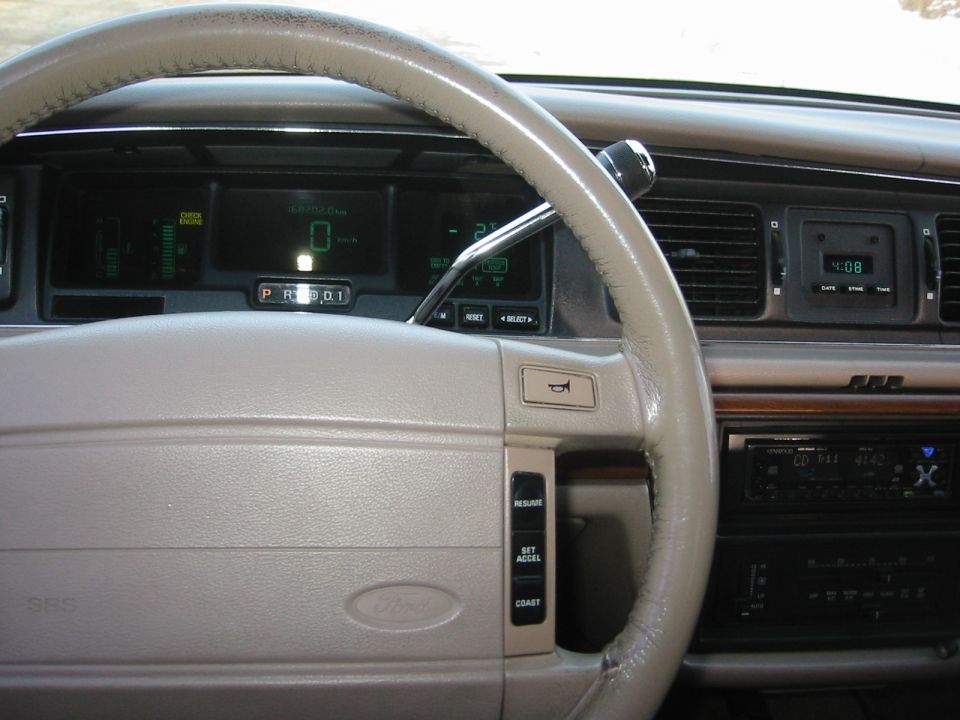 Tan dashboard and steering wheel of a 1992 Ford Crown Victoria with digital gauges and an aftermarket stereo