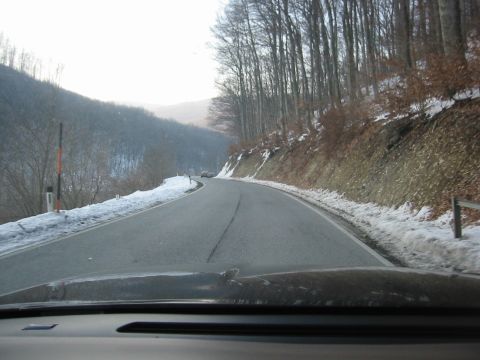 1992 Ford Crown Victoria - A car drives down a winding road covered in snow, with trees lining the hillsides.