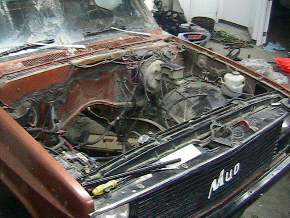 Orange 1981 Chevrolet C/K Pickup engine bay with missing engine, showing the firewall and front of the chassis