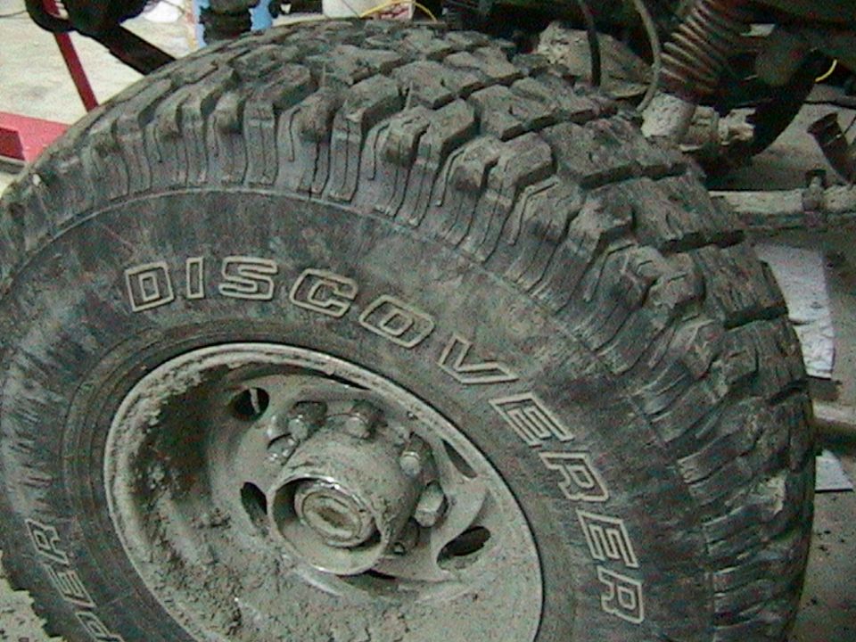 Close-up of a muddy tire with 'DISCOVERER' written on the sidewall