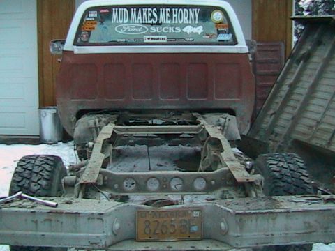 1981 Chevrolet C/K Pickup - This pickup truck is missing its body, showing only the chassis and a dump bed. A humorous sticker adorns the rear window.