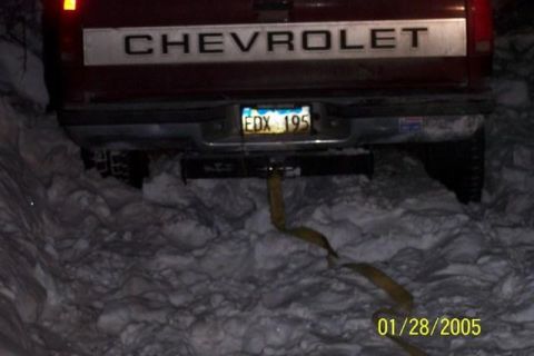 1981 Chevrolet C/K Pickup - 1981 Chevrolet C/K Pickup's rear end is visible, stuck in deep snow with a tow strap attached.