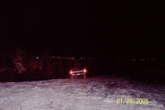 pickup truck with taillights on, driving on a snowy surface at night