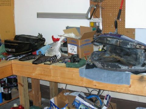 1985 Ford LTD Crown Victoria - Motorcycle fuel tanks and various tools are laid out on a workbench, suggesting a repair or restoration project.