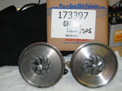 1985 Ford LTD Crown Victoria - Two turbocharger center cartridge/CHRA assemblies with compressor wheels facing up, sitting on a white cloth in front of a TurboDriven/Schw…