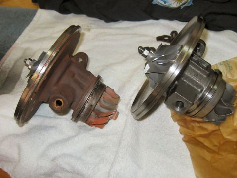 1985 Ford LTD Crown Victoria - Two turbocharger center housing rotating assemblies laid side by side on a white towel for comparison: the left cartridge is heat-discolore…