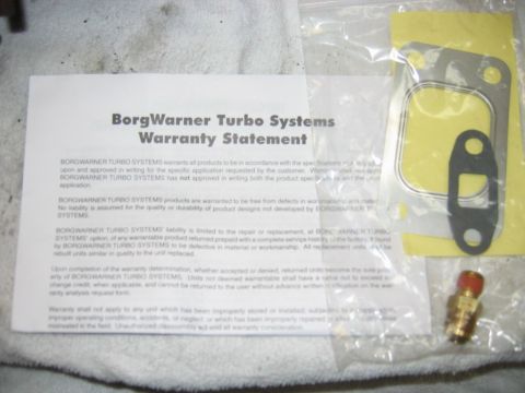 1985 Ford LTD Crown Victoria - BorgWarner Turbo Systems printed warranty statement document photographed with a gasket and fitting.
