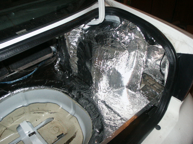 Car trunk lined with foil sound deadening mat, spare tire well exposed