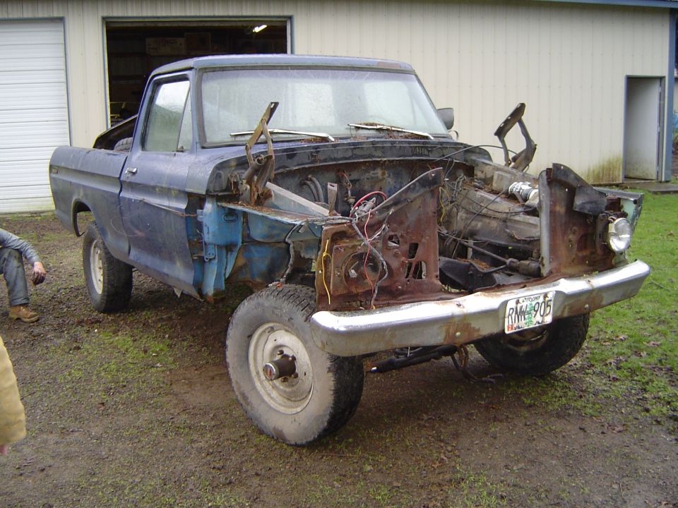 rusted 1979 Ford F-150 pickup truck, front end removed, parked outside