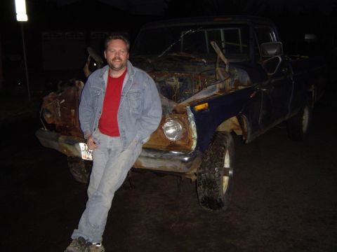 1979 Ford Bronco - A man poses with a heavily damaged and rusted blue pickup truck.