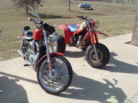 1995 Mercury Grand Marquis - Two off-road vehicles, a motorcycle and a three-wheeler, are parked outside.