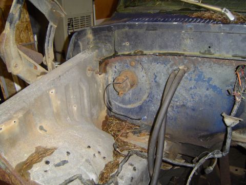 1979 Ford Bronco - The engine bay of a blue vehicle shows significant rust and debris, suggesting it is a parts truck.