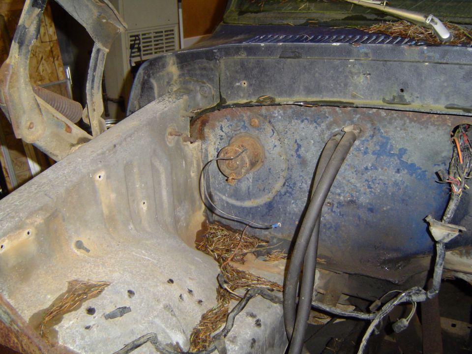 Engine bay of a blue vehicle with rust and nesting material