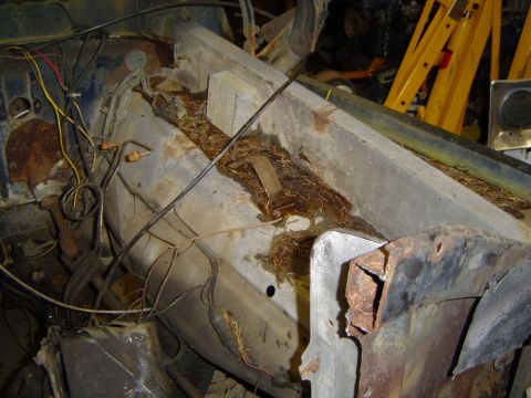 1979 Ford Bronco - This photo shows the rusted firewall of a vehicle, filled with debris and exposed wiring.