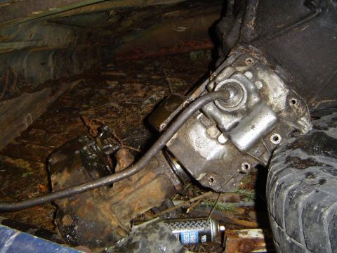 1979 Ford Bronco - A close-up view of a vehicle's transmission and a tire, surrounded by debris and dirt.