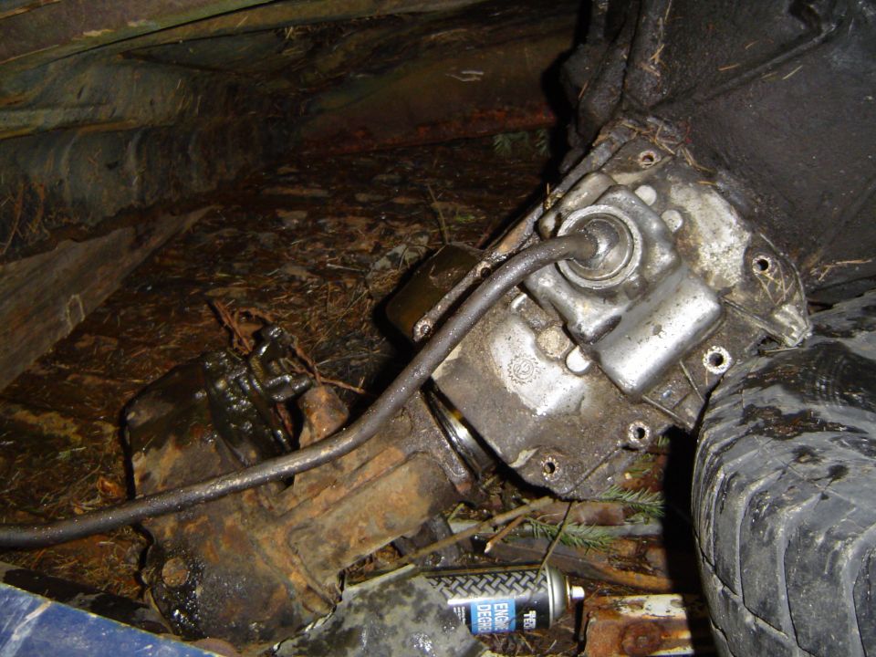 close-up of a dirty vehicle transmission and a tire