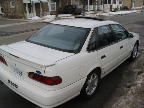 1993 Ford Taurus - A white 1993 Ford Taurus SHO is parked on a residential street with snow on the ground.