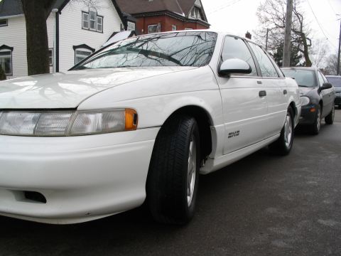 1993 Ford Taurus - White 1993 Ford Taurus parked on a street with another vehicle behind it.