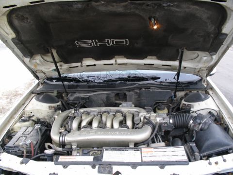 1993 Ford Taurus - The engine bay of a 1993 Ford Taurus SHO is shown, its V6 engine and distinctive SHO badging on the hood liner.