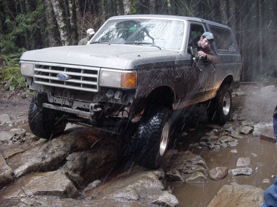 Ford Bronco navigating rocky terrain with a driver visible