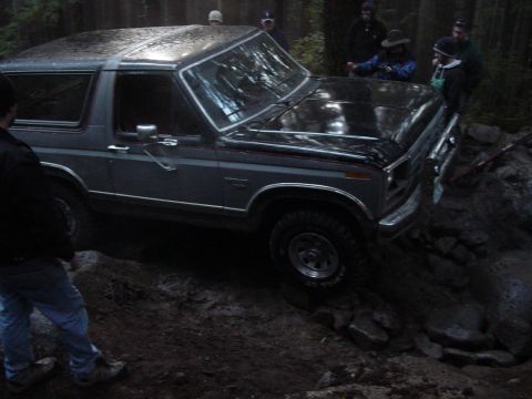 1987 Ford Bronco - Ford Bronco tackling a challenging off-road trail with onlookers present.