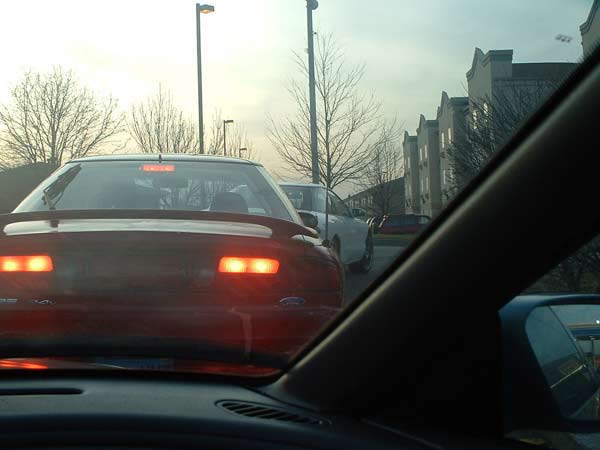 Red 1993 Ford Probe from rear, brake lights illuminated, in traffic