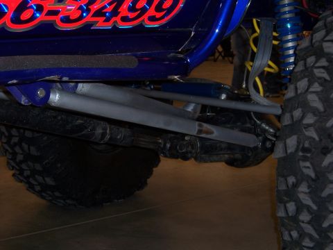1999 Jeep TJ - Close-up of a modified blue Jeep's suspension system and off-road tire.