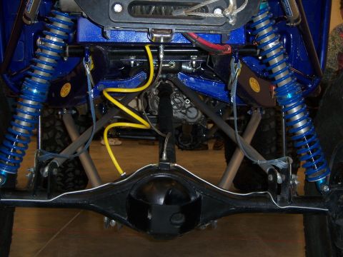 1999 Jeep TJ - Undercarriage view of a modified off-road vehicle, highlighting its rear axle and suspension system with bright blue shocks.