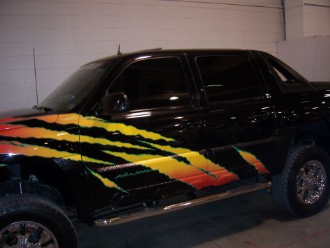 1999 Jeep TJ - This black pickup truck features a flame graphic design on its side, with the word 'AVALANCHE' visible on the door.