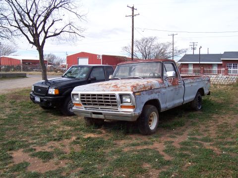 1979 Ford F-100 - A weathered 1979 Ford F-100 pickup truck sits parked next to a black Ford Ranger.