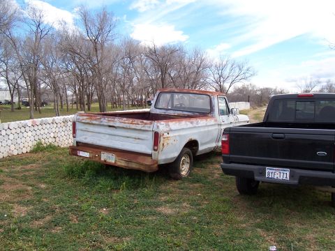 1979 Ford F-100 - Two Ford pickup trucks, one older and rusty, the other a newer model, are parked outdoors.
