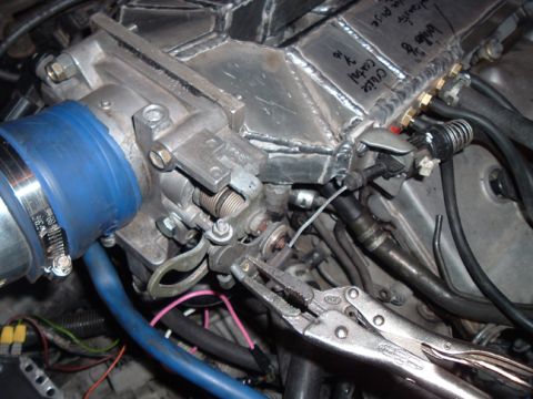 1994 Ford Probe - Close-up of a custom intake manifold assembly, showing the throttle body, blue intake hose, and wiring, with vise grips attached to a cable.