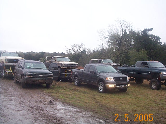 Several trucks and SUVs parked on muddy ground